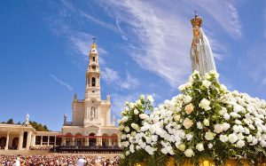 Imagem mostra Santuário de Fátima com uma representação em estátua de Nossa Senhora de Fátima em primeiro plano